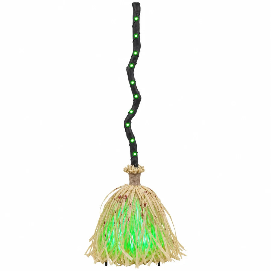 The witch broom standing upright on white, its handle lit green from end to end