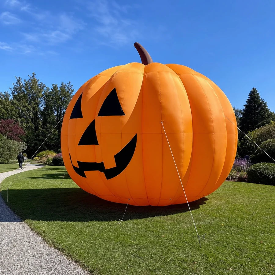 Three-quarter daylight view of the giant inflatable pumpkin on an open front lawn beside a garden path